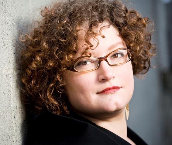 April Viczko stands by a wall looking towards the camera.